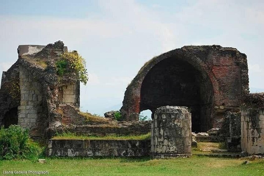Ancient ruins with a large arched structure and stone walls. 3