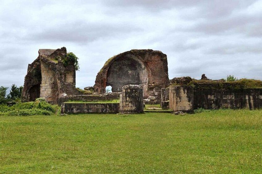 Ancient ruins with arches and stone walls in a grassy field. 2