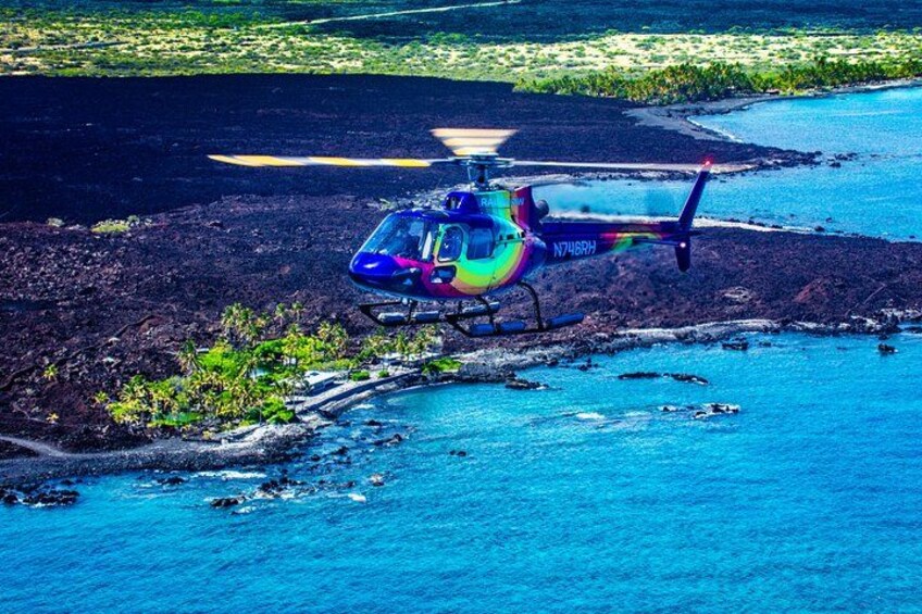 A helicopter over a coastal area with a clear view of the ocean and a small island. 2