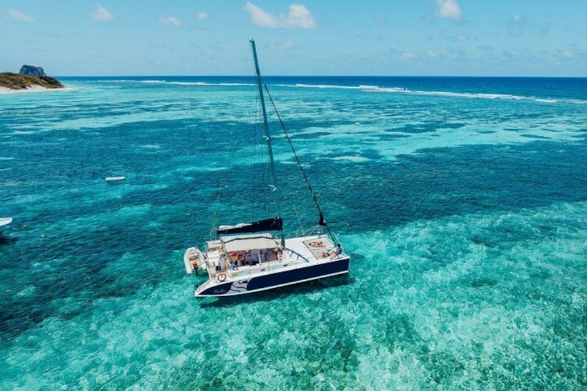 A sailboat anchored in clear turquoise waters with a distant island. 1