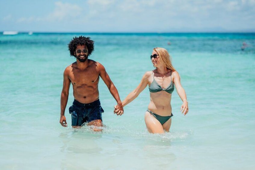 Two people walking in shallow water at a beach. 2