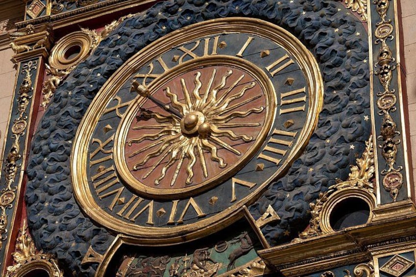 A detailed clock with Roman numerals and a sun motif. 2