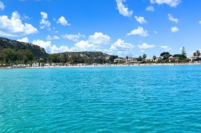 Una spiaggia costiera con acque turchesi cristalline, una riva sabbiosa e un paesaggio collinare sullo sfondo. 5