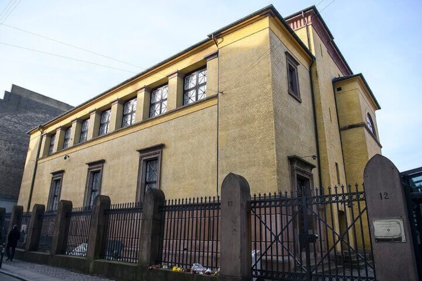 Een geel gebouw met een zwart metalen hek en een poort, nummer 12. 1