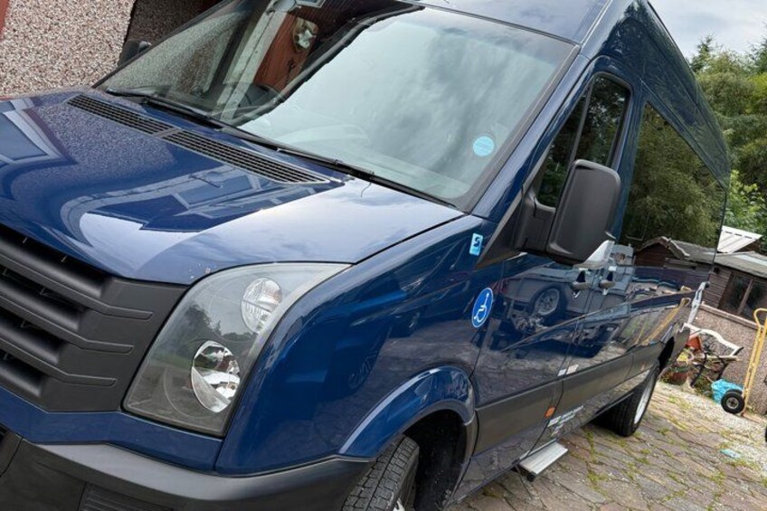 A blue van parked on a cobblestone driveway. 2