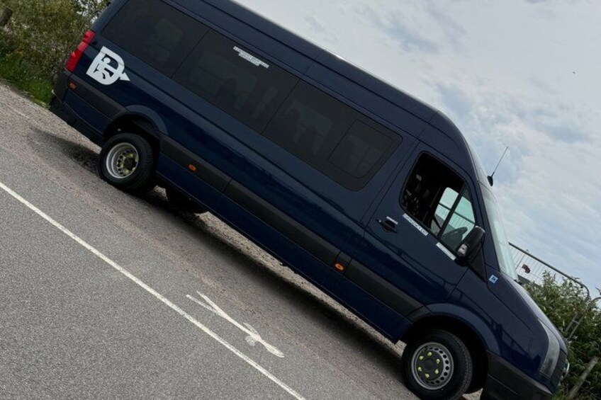 A dark blue van parked on a road with white lane markings. 1