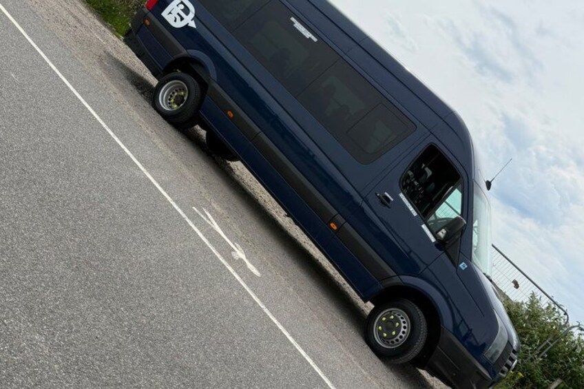A dark blue van parked on a road with white lane markings. 3