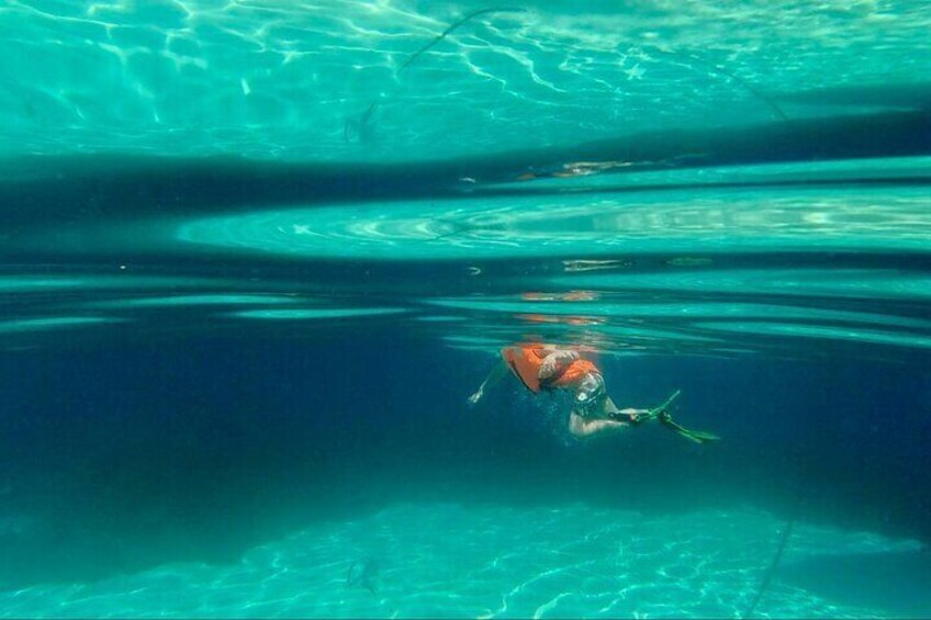 A person swimming underwater in clear blue water. 1