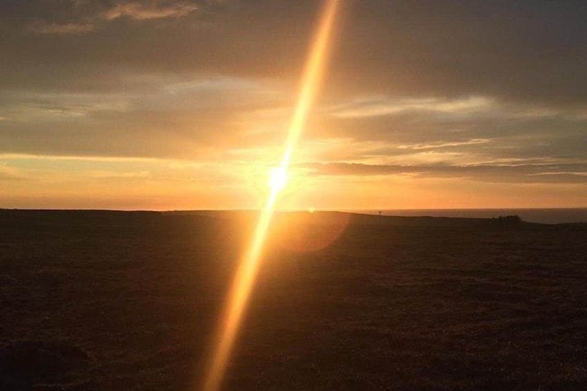 A sunset over a flat landscape with a visible sunbeam. 2