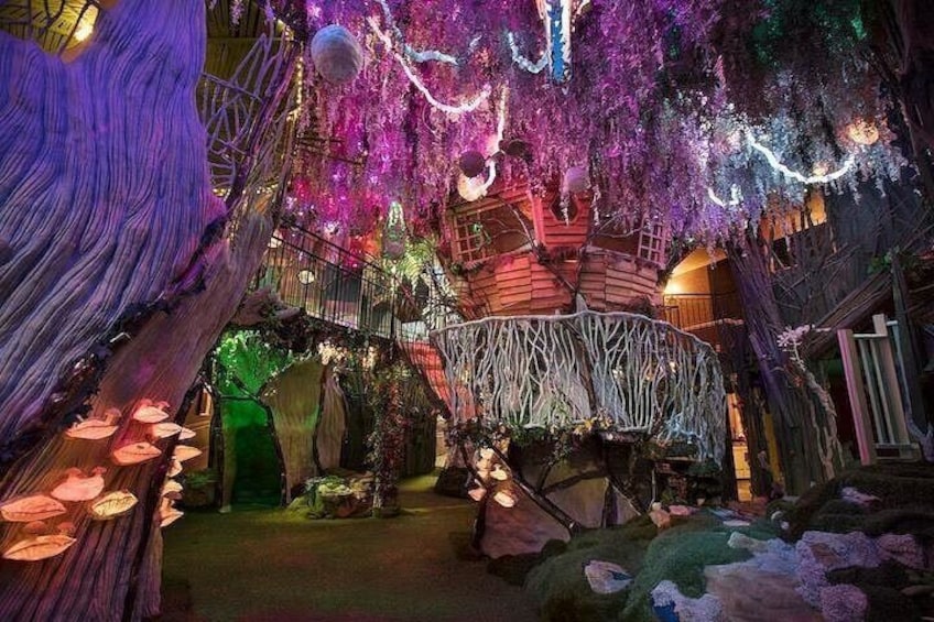 Een boomhut met een wenteltrap, omringd door kleurrijke lichtjes en decoraties. 3