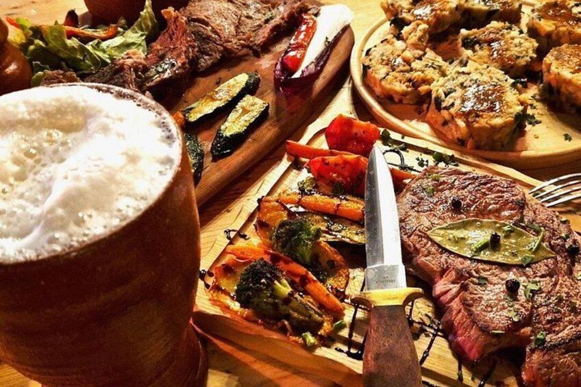 A meal with grilled meat, vegetables, and a beer. 3