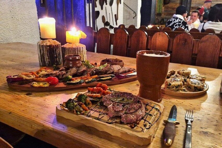 A wooden table with a variety of grilled meats, a large beer mug, and a knife and fork on the right side. 2