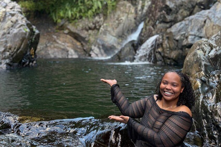 A person sitting by a rocky stream with water flowing over rocks. 5