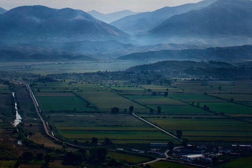 A rural landscape with fields, a river, and distant mountains. 3
