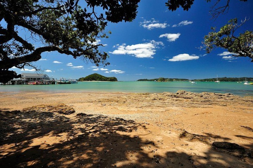 Une plage avec une jetée, une eau d’un bleu limpide et une petite île qui se dessine à l’horizon. 4