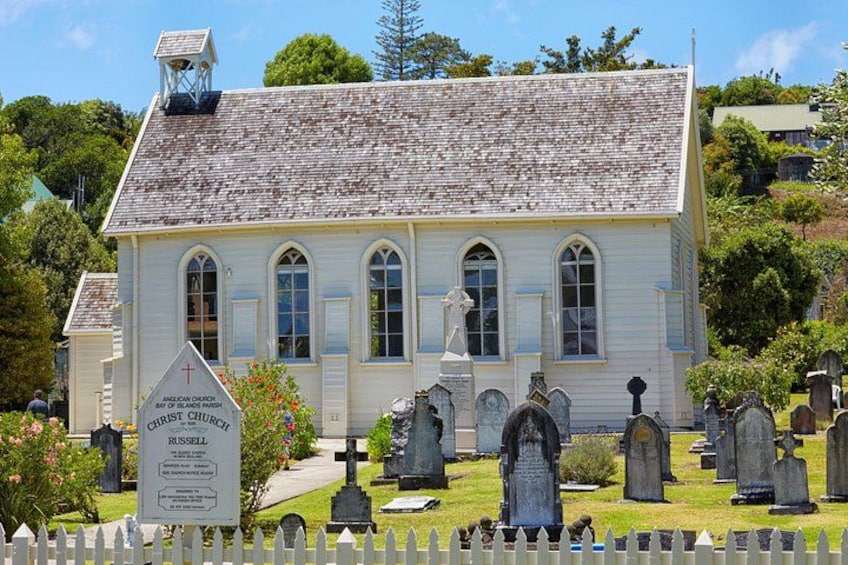 Une église blanche, dotée d’un clocher, entourée d’un cimetière où se dressent des pierres tombales. 5