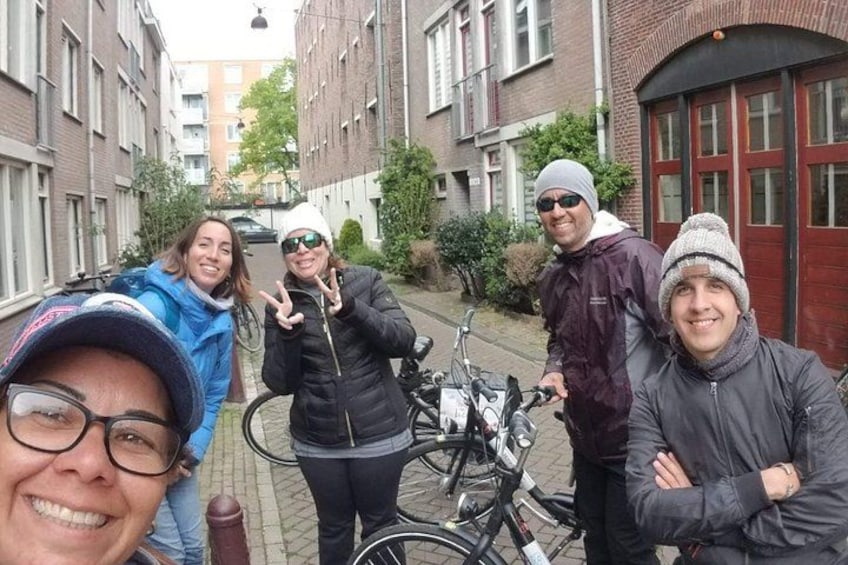 A group of people standing in a narrow street with bicycles parked on the side. 5