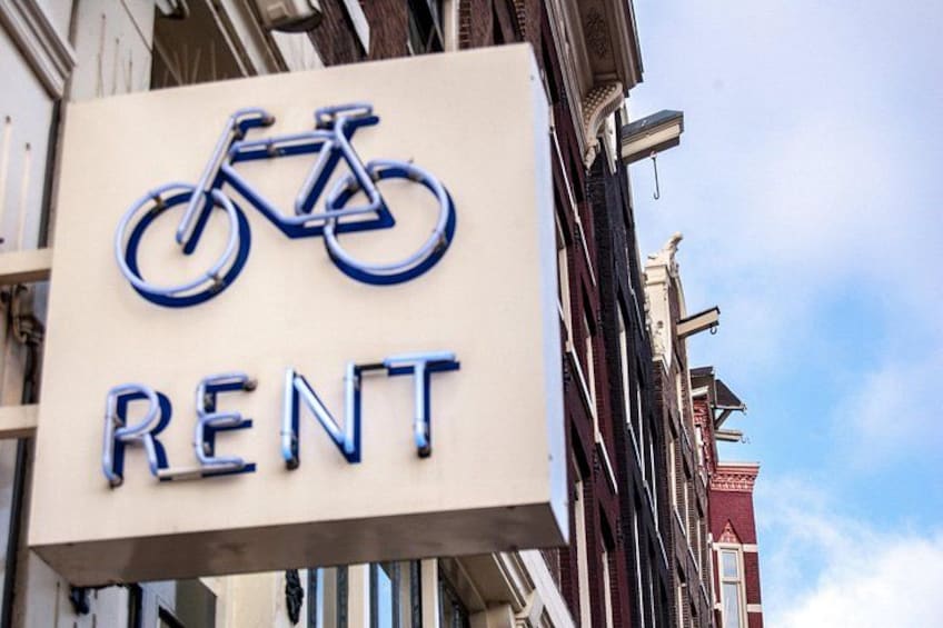 A sign with a bicycle symbol and the word 'RENT' on a building. 2