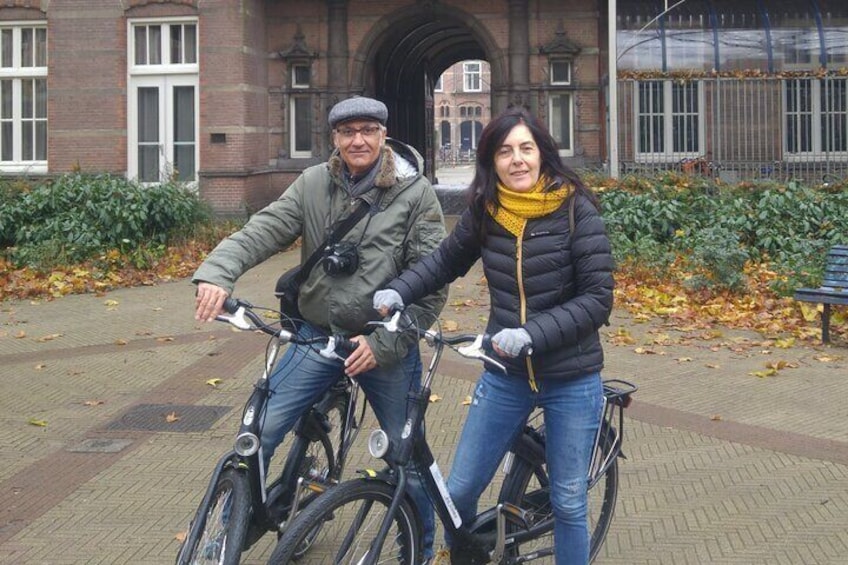 Two people on bicycles in front of a brick building with a large archway. 4