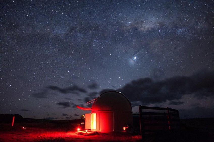 A dome-shaped structure illuminated by red lights, set against a starry night sky with visible clouds. 2