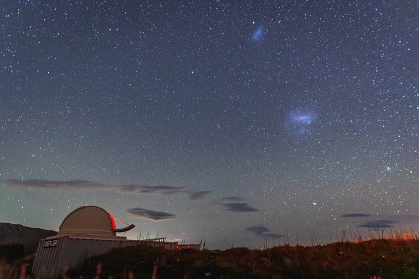 A starry night sky with a telescope and a dome structure. 5