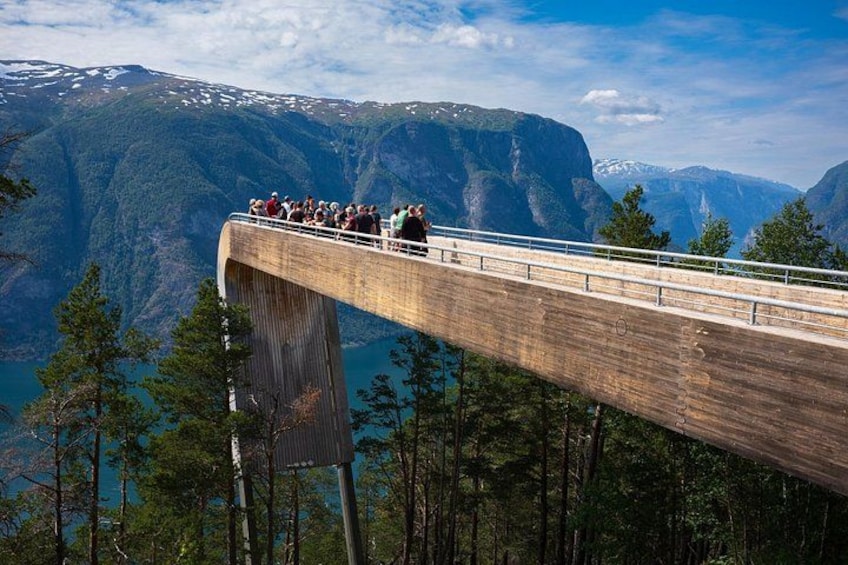 Un puente de madera con gente caminando, rodeado de bosque y montañas. 1
