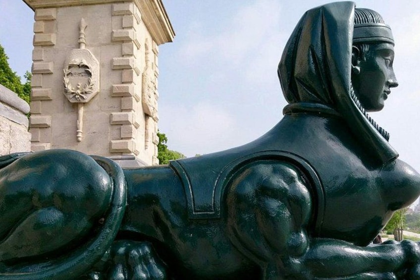 A statue of a reclining figure with a headpiece, set against a stone structure with a carved face. 5