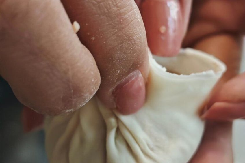 A hand holding a piece of dough, possibly doughnut or pastry, with a visible filling. 3