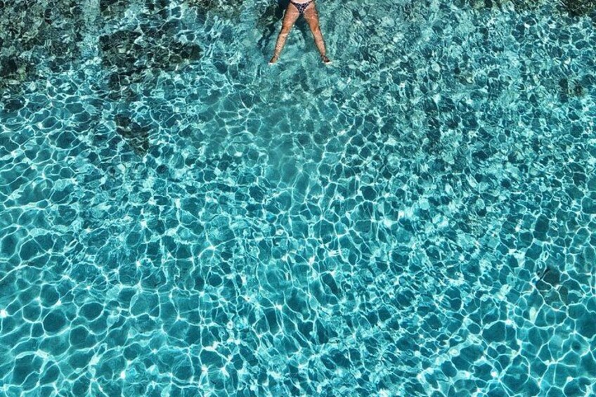 A person standing in a clear blue pool with visible ripples on the water surface. 5