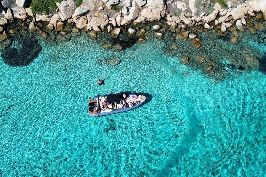 A boat on clear turquoise water with a rocky shoreline. 4