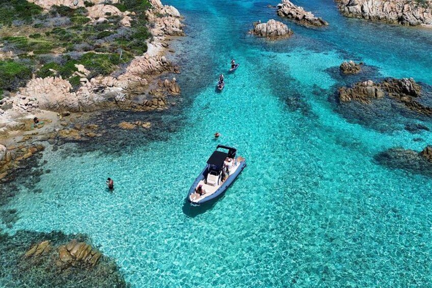 A boat on clear turquoise water surrounded by rocky formations. 3