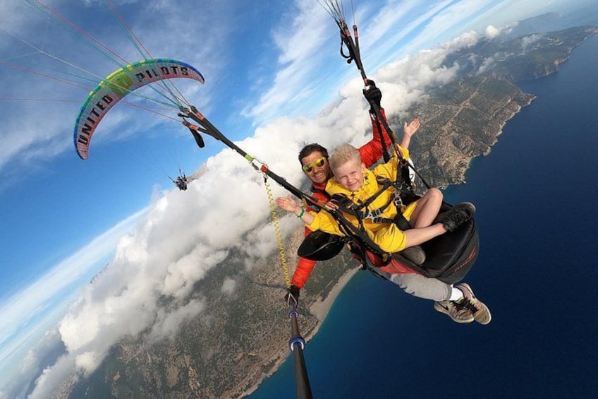 Una persona practica paratrike sobre un paisaje costero con nubes abajo. 1
