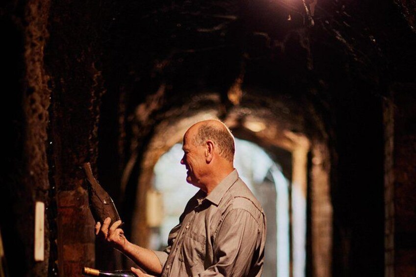 A man holding a hammer, standing in a tunnel with a brick wall and an arched opening. 3