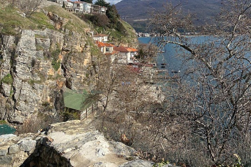 A coastal cliff with houses, a rocky path, and a body of water. 2