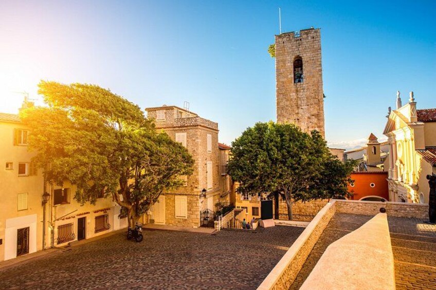 A cobblestone street, a stone tower, and buildings with balconies. 2