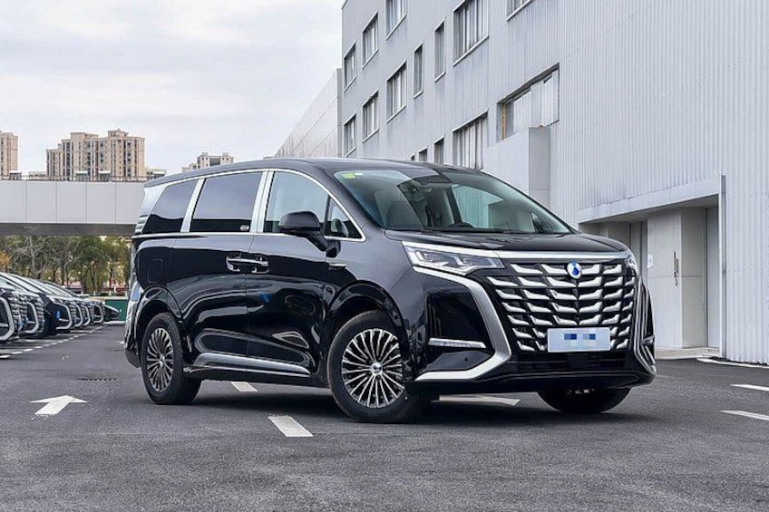 A black minivan parked in a lot with a modern building in the background. 3