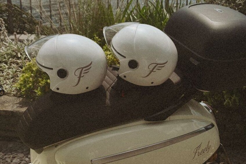 A vintage scooter with two white helmets featuring a stylized 'F' logo. 3