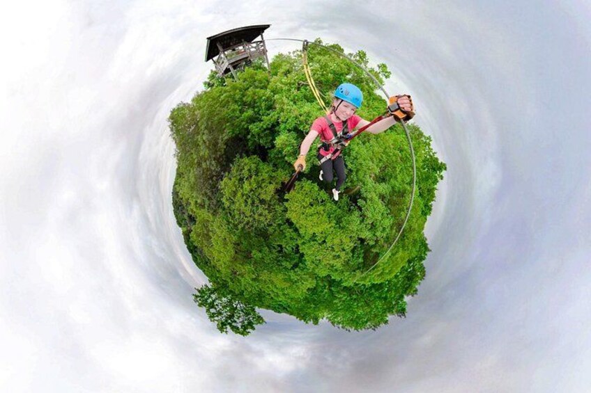 En person som hoppar bungyjump från en plattform omgiven av frodig grönska. 1