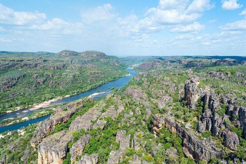 A river winding through a mountainous landscape with dense greenery and rocky cliffs. 1