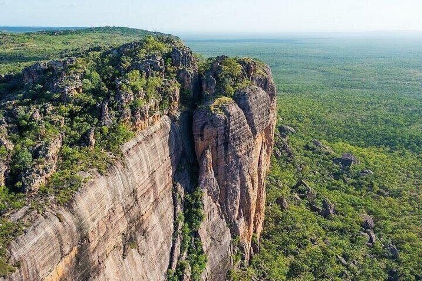 A large rock formation with steep cliffs and sparse vegetation. 5