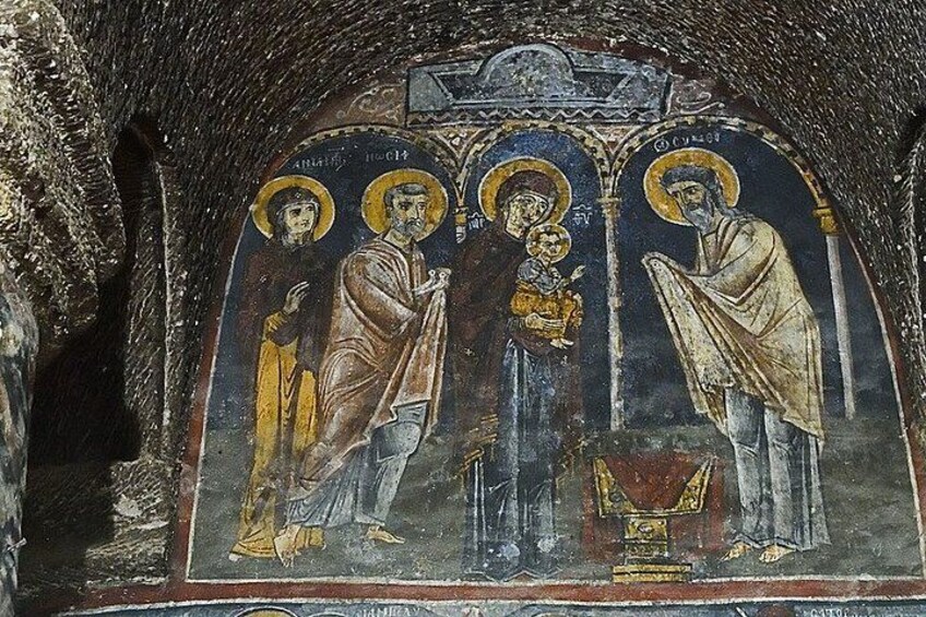 A mosaic with three figures, one holding a child, in a dimly lit cave. 2