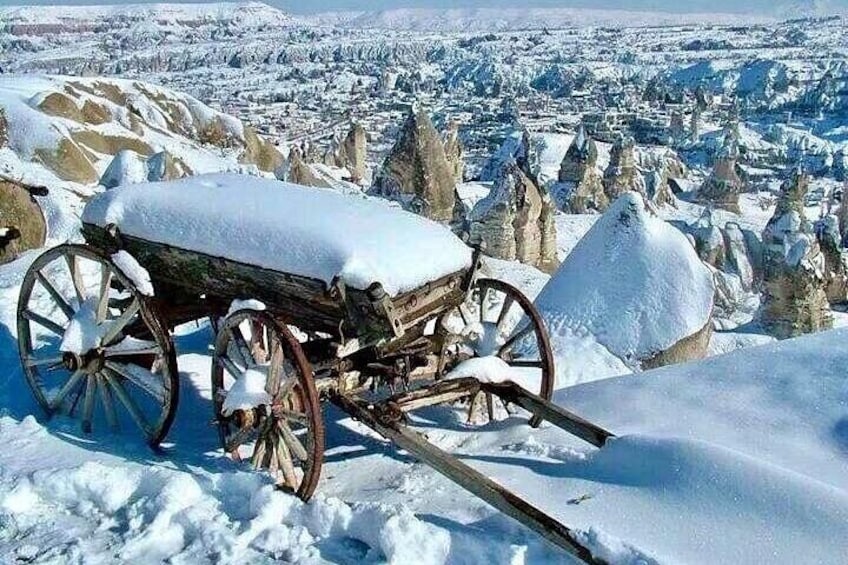 A snow-covered wooden cart on a snowy mountain with a town in the background. 5