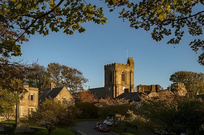 A historic building with a tower, surrounded by trees and a paved path. 4