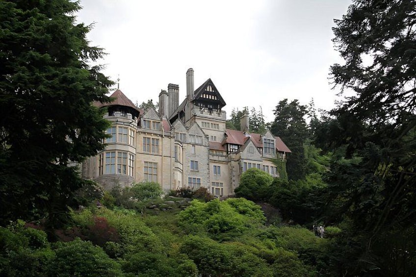 A large, historic building surrounded by dense greenery. 5