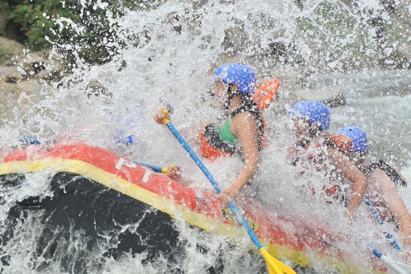 People in a red and yellow raft navigating through a turbulent river. 2