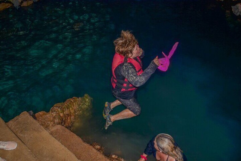 A person jumping into a pool with a pink toy. 2