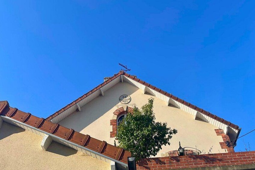 A building with a red-tiled roof, a brick chimney, and a clear blue sky. 4