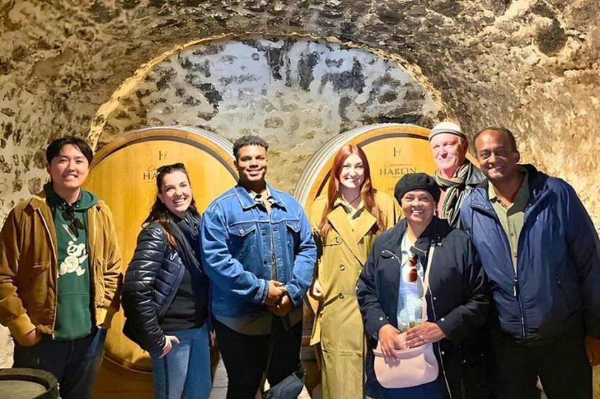 A group of people standing in front of large wooden barrels. 3