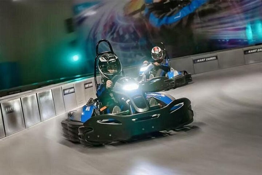 Two go-karts on a track with barriers and a blurred background. 1