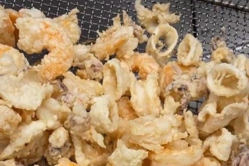 A close-up of fried food items, likely calamari, on a wire rack. 3